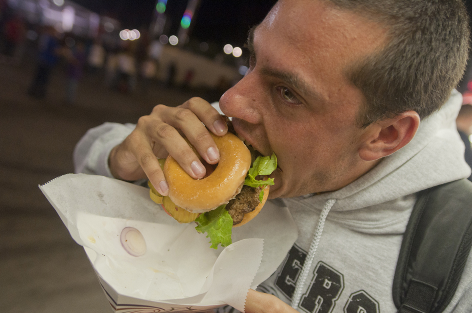 A new friend chows down on this year's notorious donut cheeseburger. Photo by Michael Cooper.