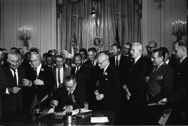 Lyndon B. Johnson signs the Civil Rights Act of 1964.